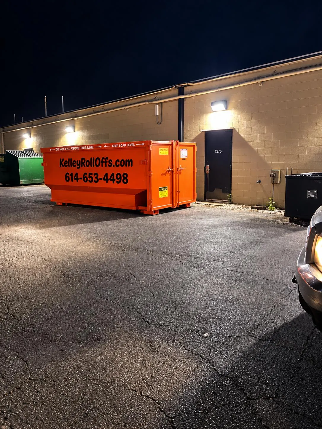 Kelley Roll-Offs dumpster next to a commercial building at night